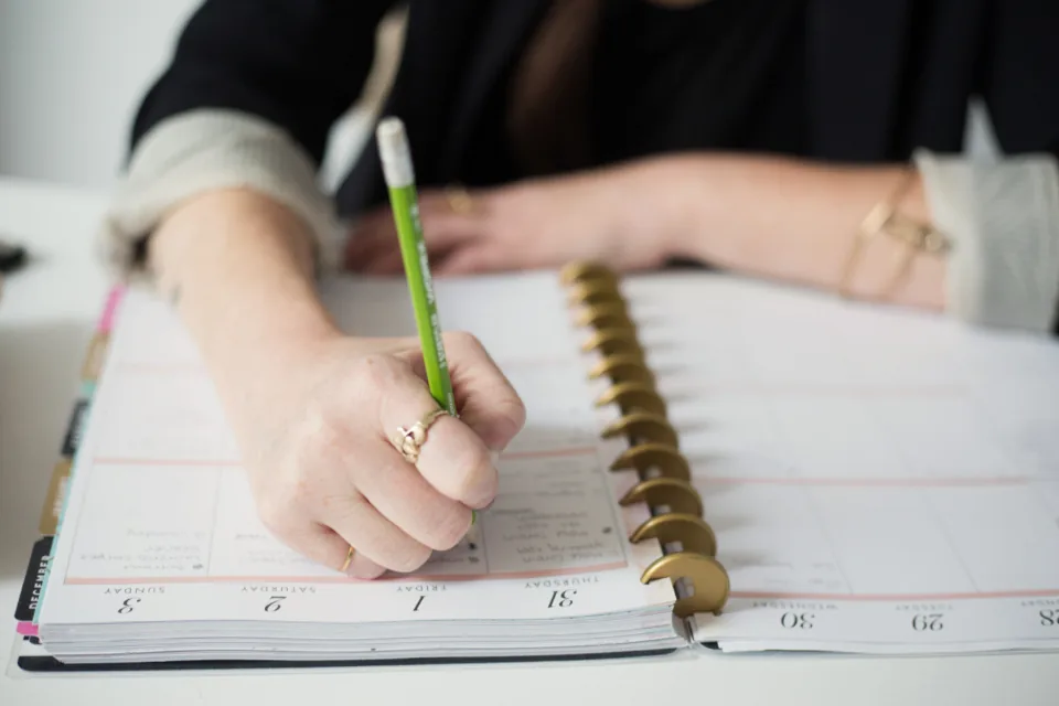 Une main écrit dans un agenda hebdomadaire : quinze minutes le lundi matin, et c'est tout